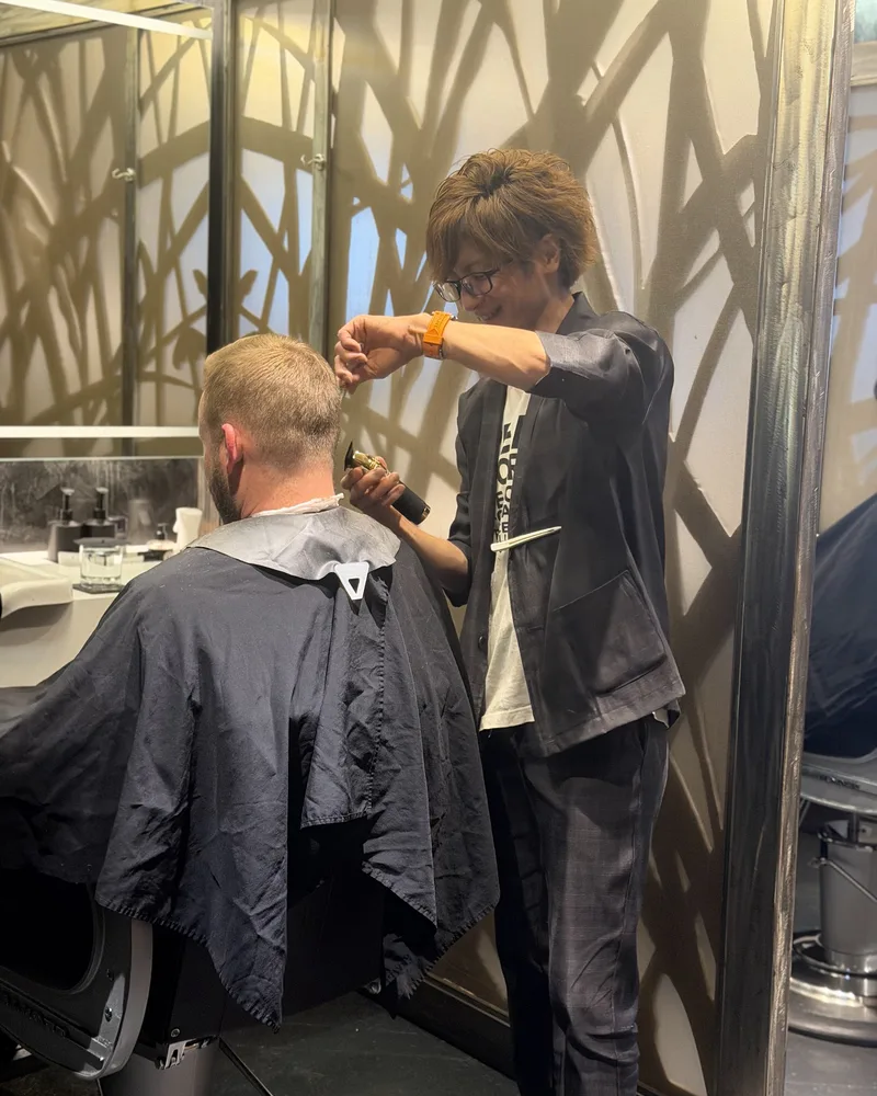 A stylist cutting a guest’s hair with scissors at the Martial Vivot Midtown salon, seen from behind