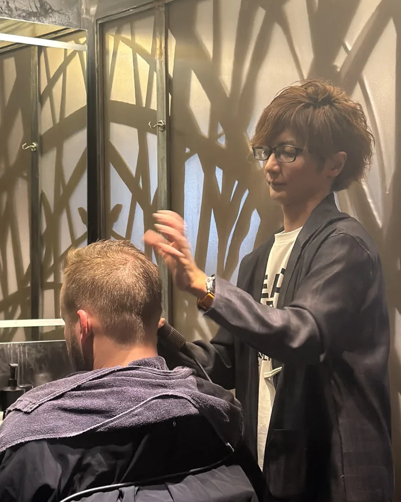 A barber finishing the sideburn line with a clipper at the Martial Vivot Midtown salon