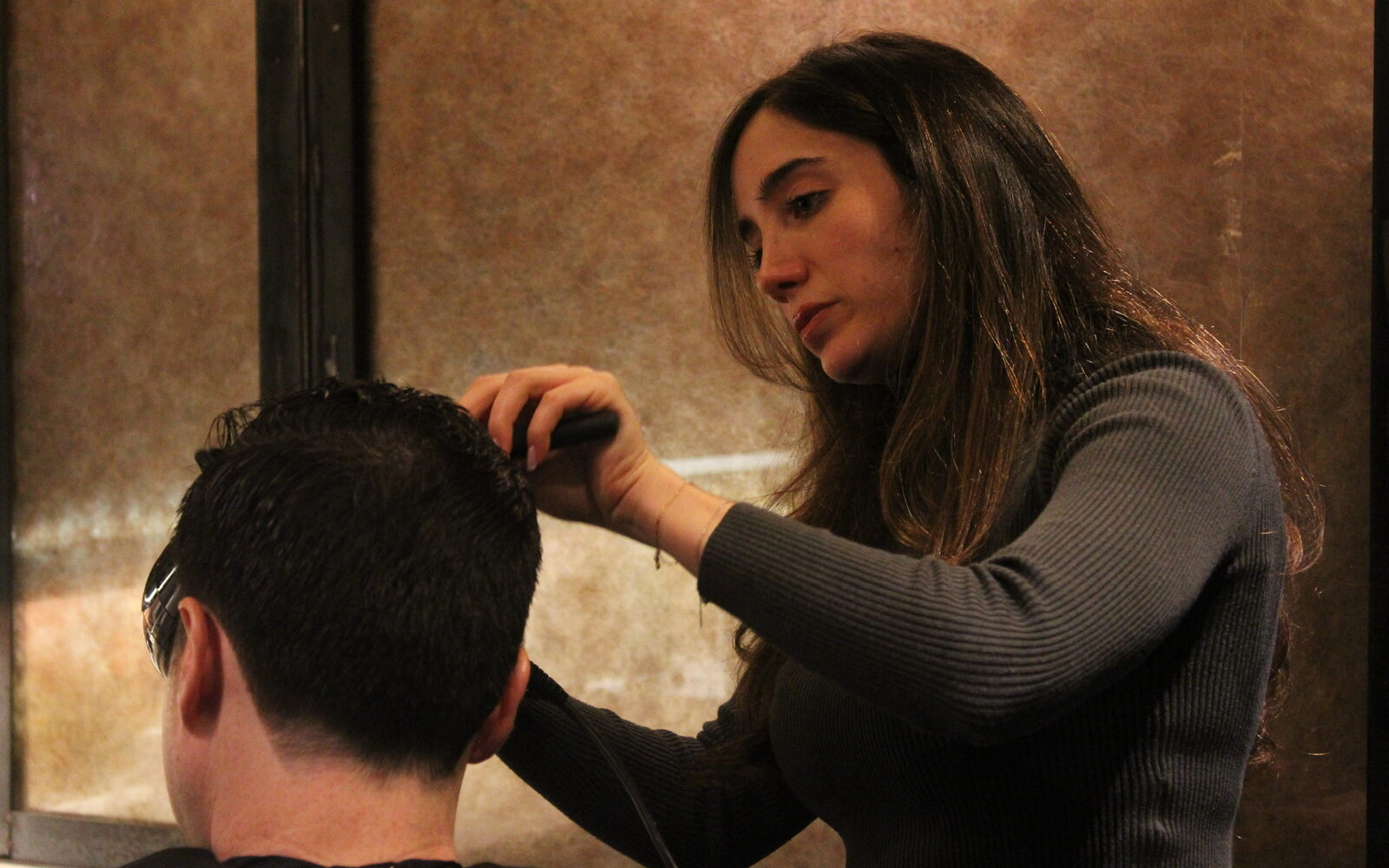 A Martial Vivot stylist cutting a client's hair mid-appointment at a New York styling station