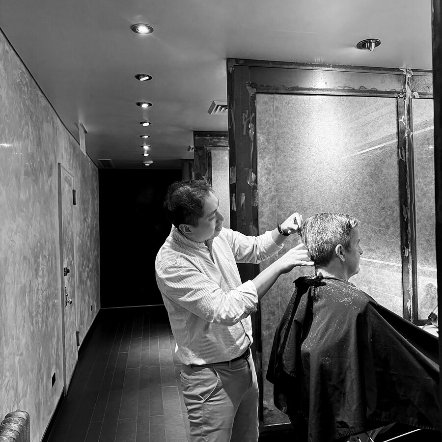 A tint brush and bowl of hair color on a dark ground — gray blending at Martial Vivot Salon Pour Hommes