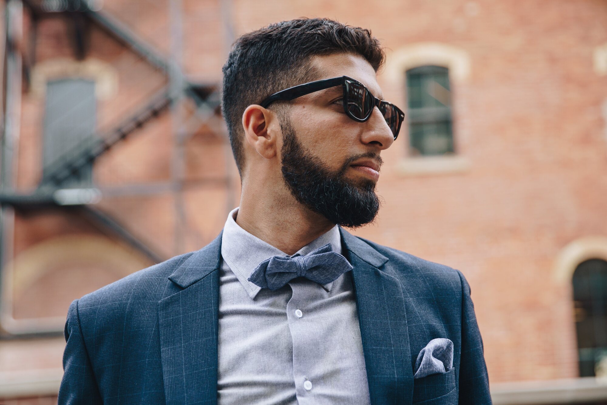 A groomed man in a tailored suit and bow tie on a New York street